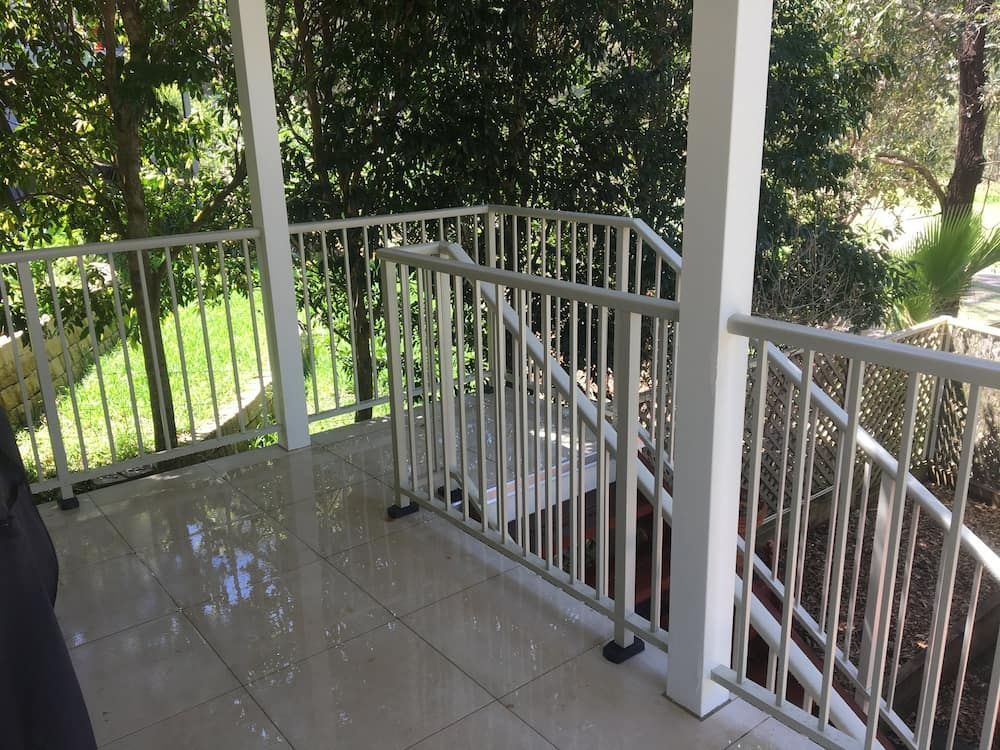 A Balcony With a White Railing and Stairs Leading Up to It — Riverside Aluminium & Stainless in Coolongolook, NSW