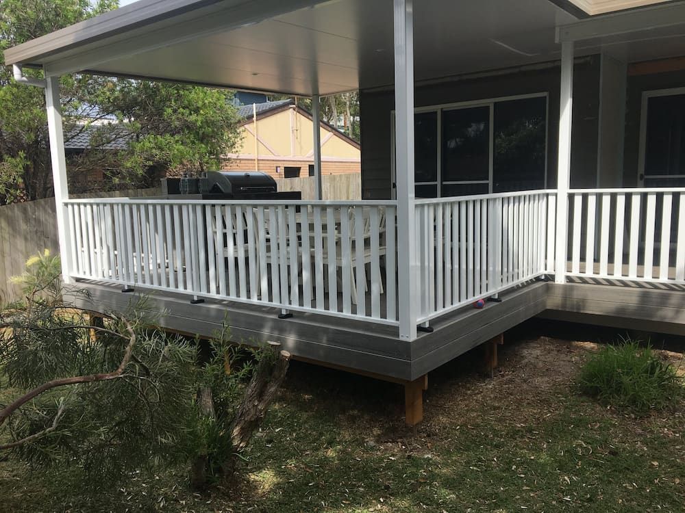 A Porch With a White Railing and a Table and Chairs on It — Riverside Aluminium & Stainless in Gloucester, NSW