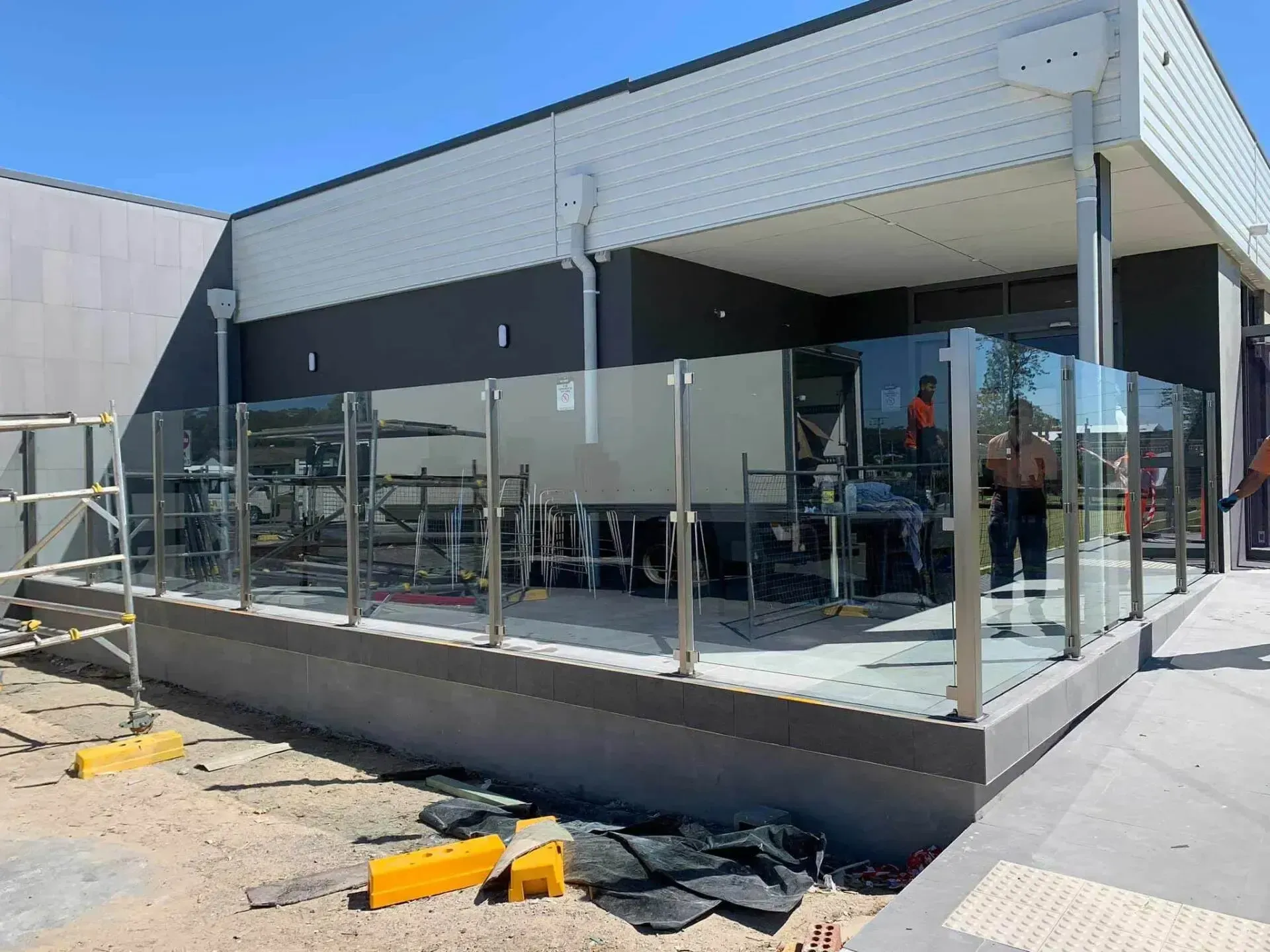 A glass railing is being installed on the side of a building — Riverside Aluminium & Stainless in Coolongolook, NSW