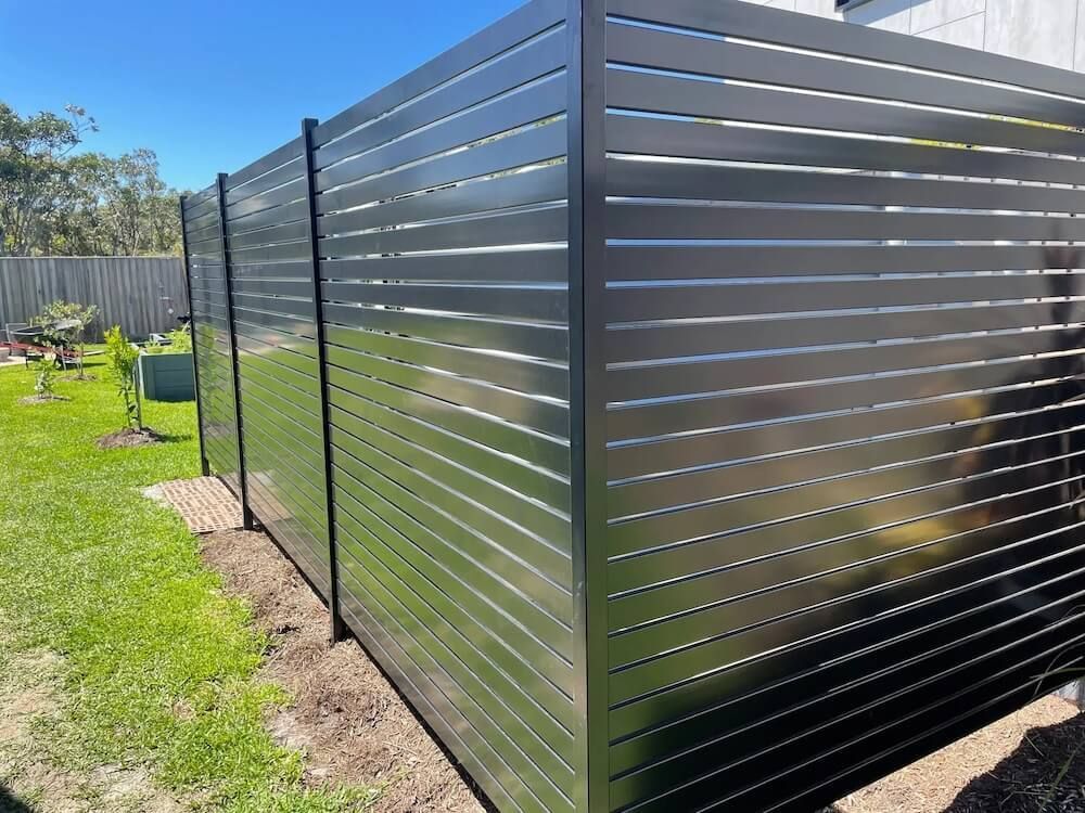 A stainless steel fence is surrounding a lush green yard — Riverside Aluminium & Stainless in Coolongolook, NSW