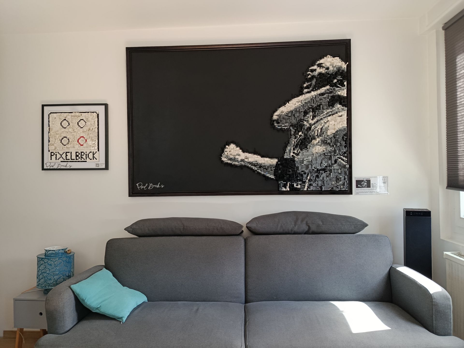 Salon avec canapé, grand tableau noir et blanc d'un boxeur, petit tableau encadré et haut-parleurs.