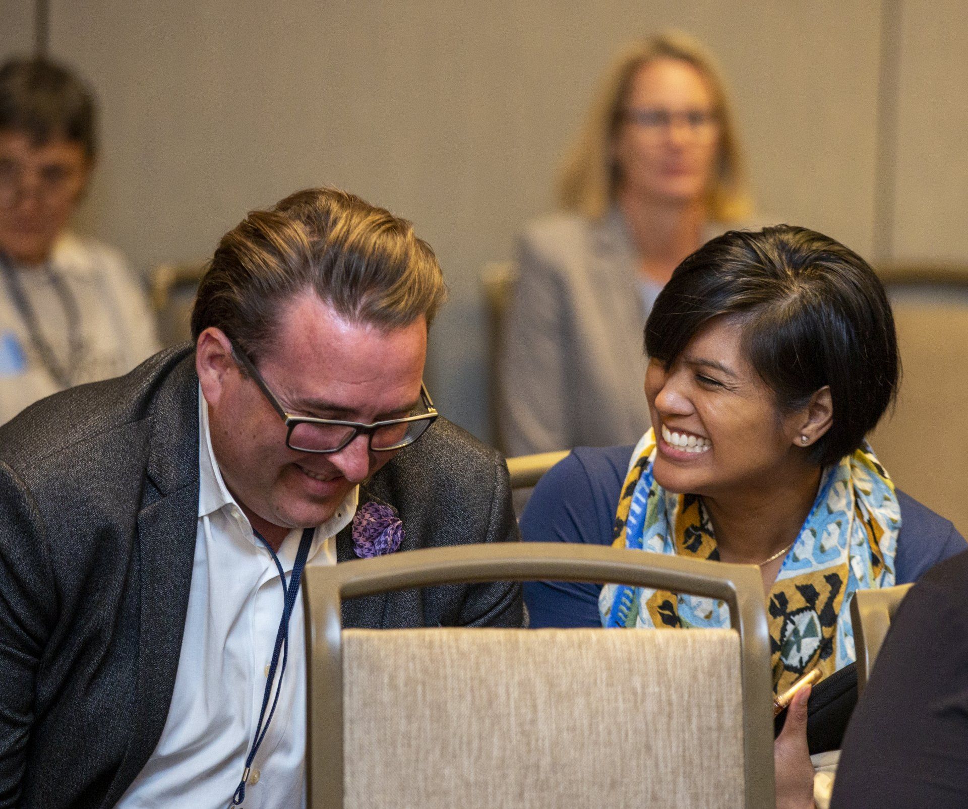 Two people laughing while at a conference.