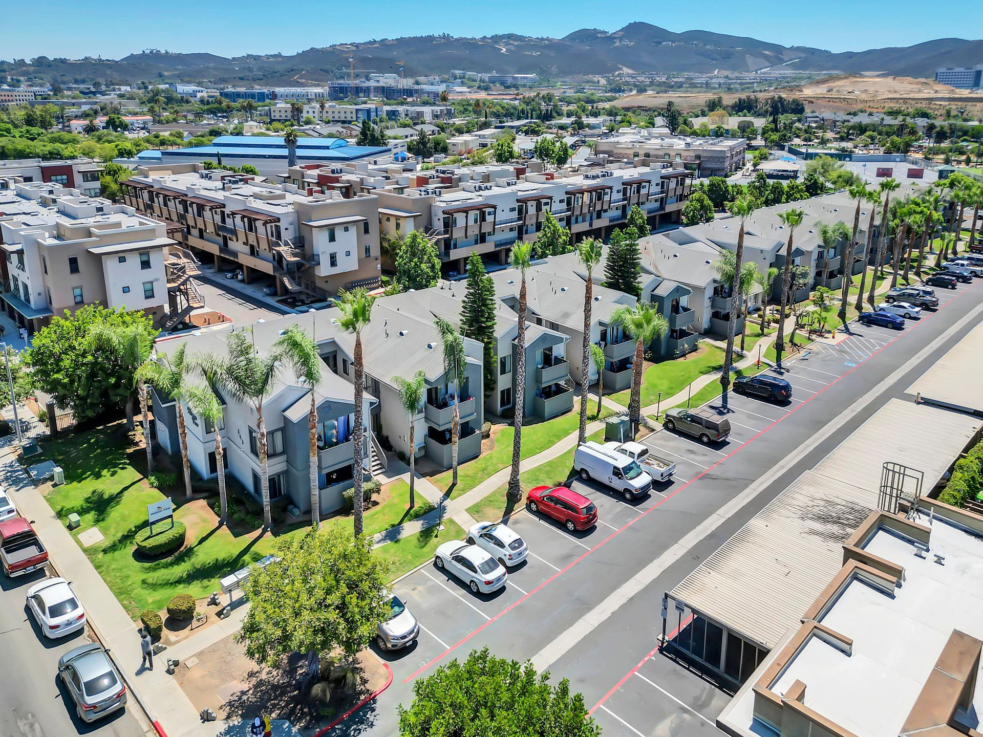 An aerial view of a apartment complex with cars parked in front of it.