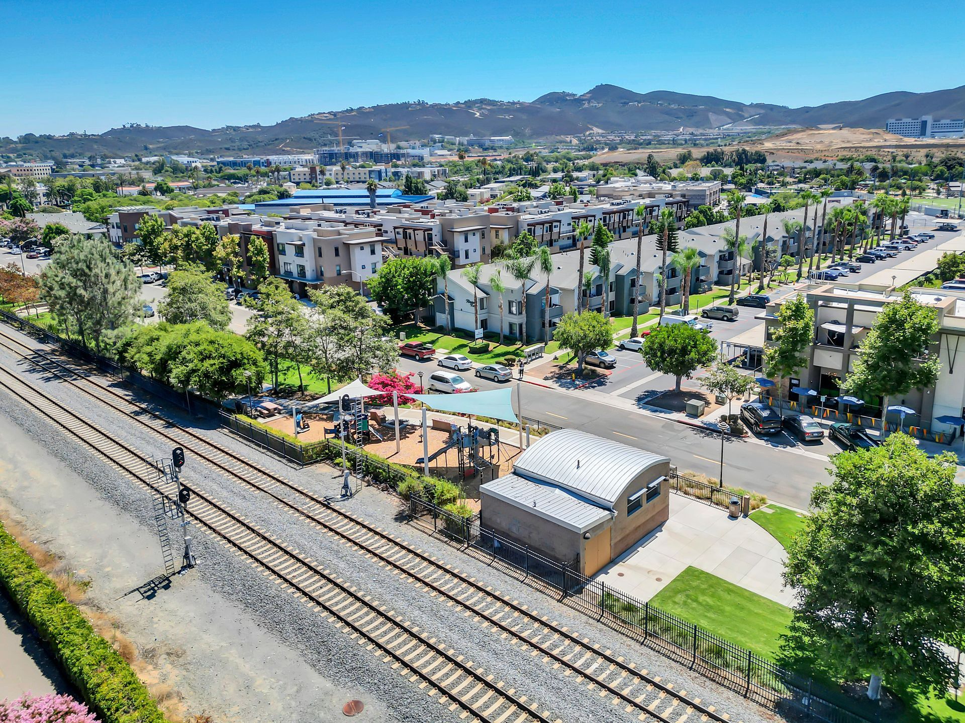 An aerial view of a city with a train track in the foreground and a playground in the background.