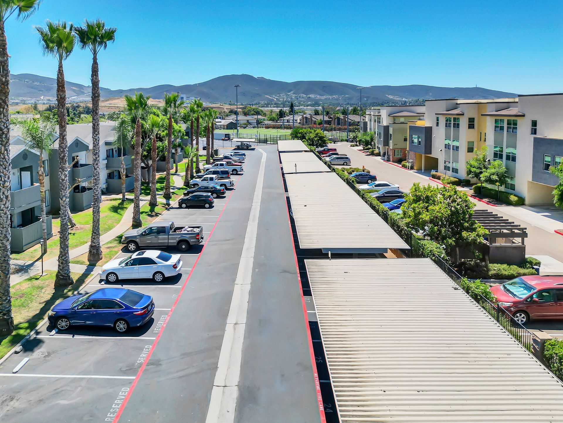 An aerial view of a parking lot with cars parked in front of a building.