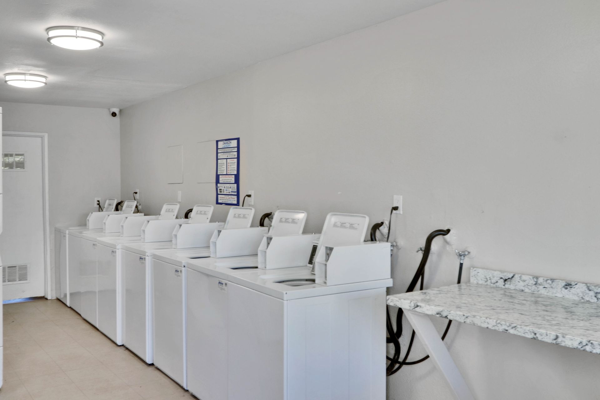 A laundromat with a row of white washers and dryers.