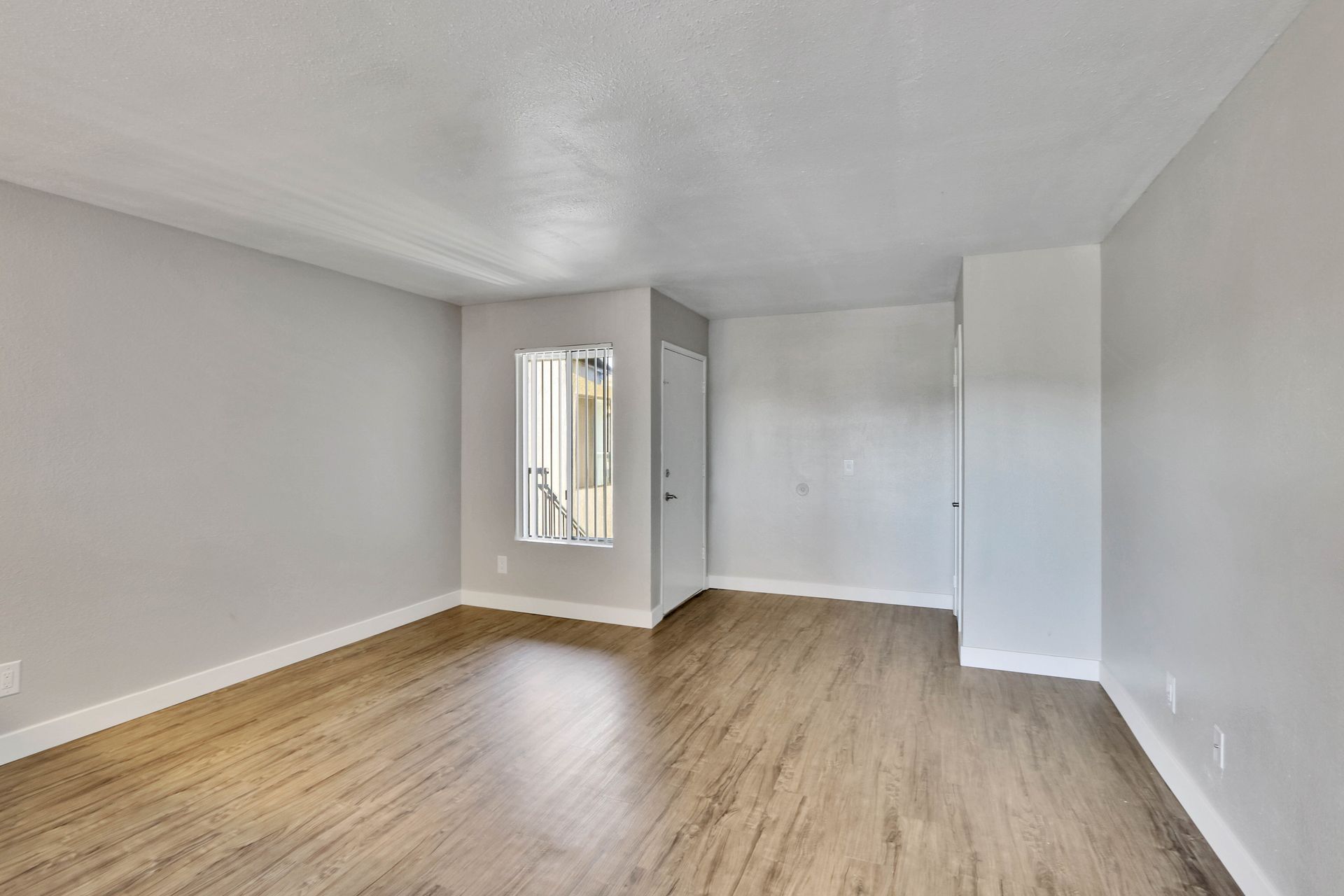 An empty living room with hardwood floors and a window.