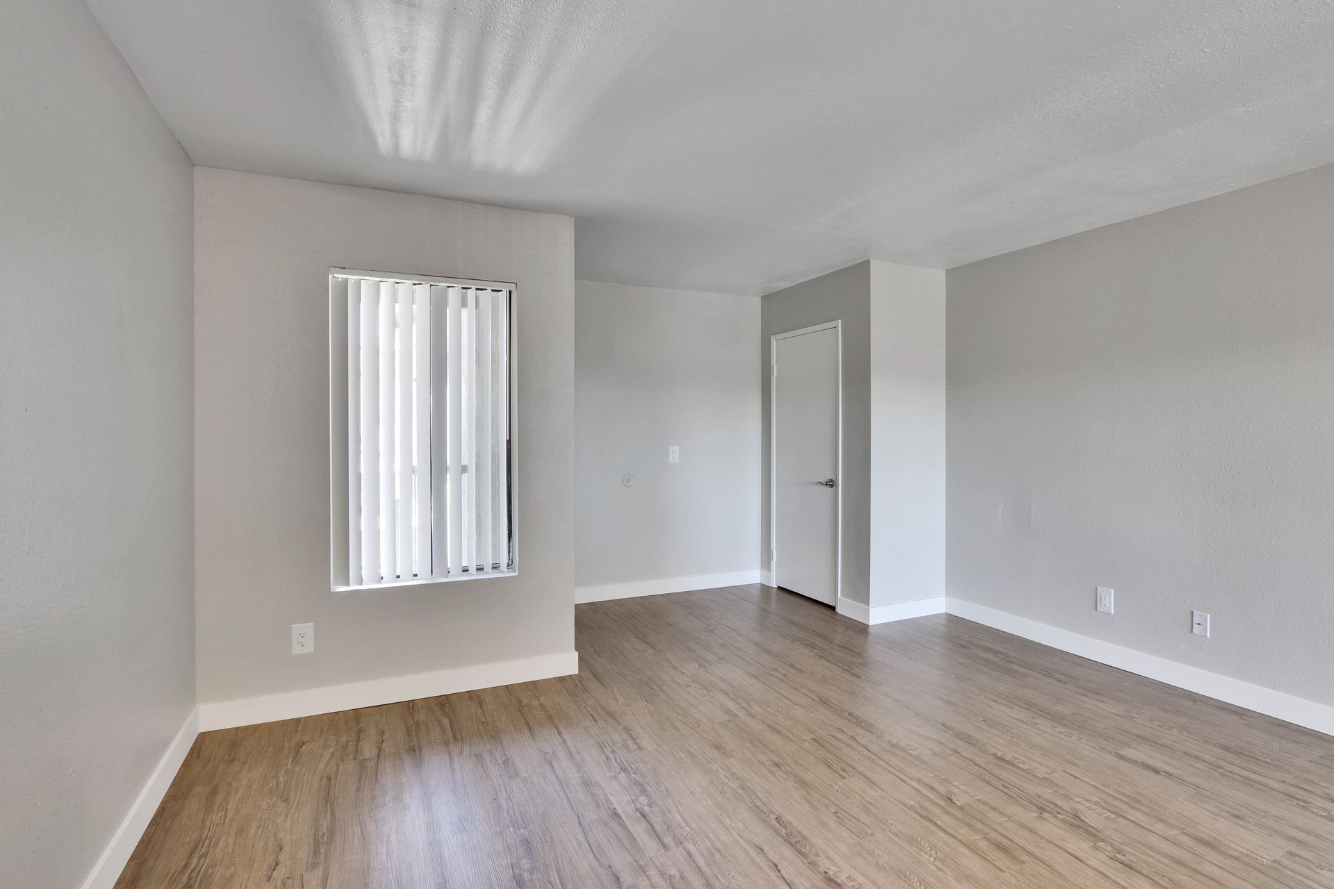 An empty living room with hardwood floors and a window.