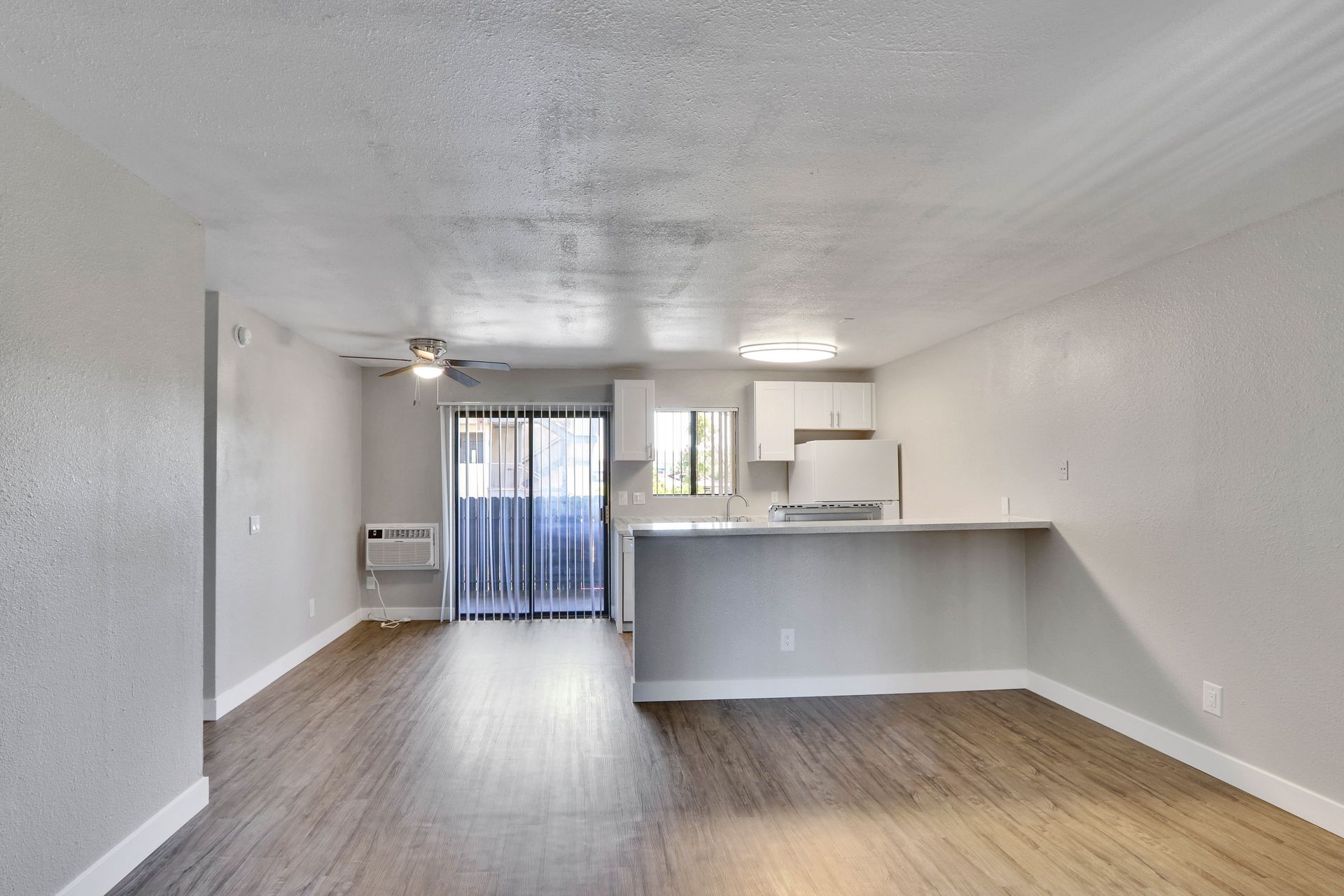 An empty apartment with a kitchen and sliding glass doors