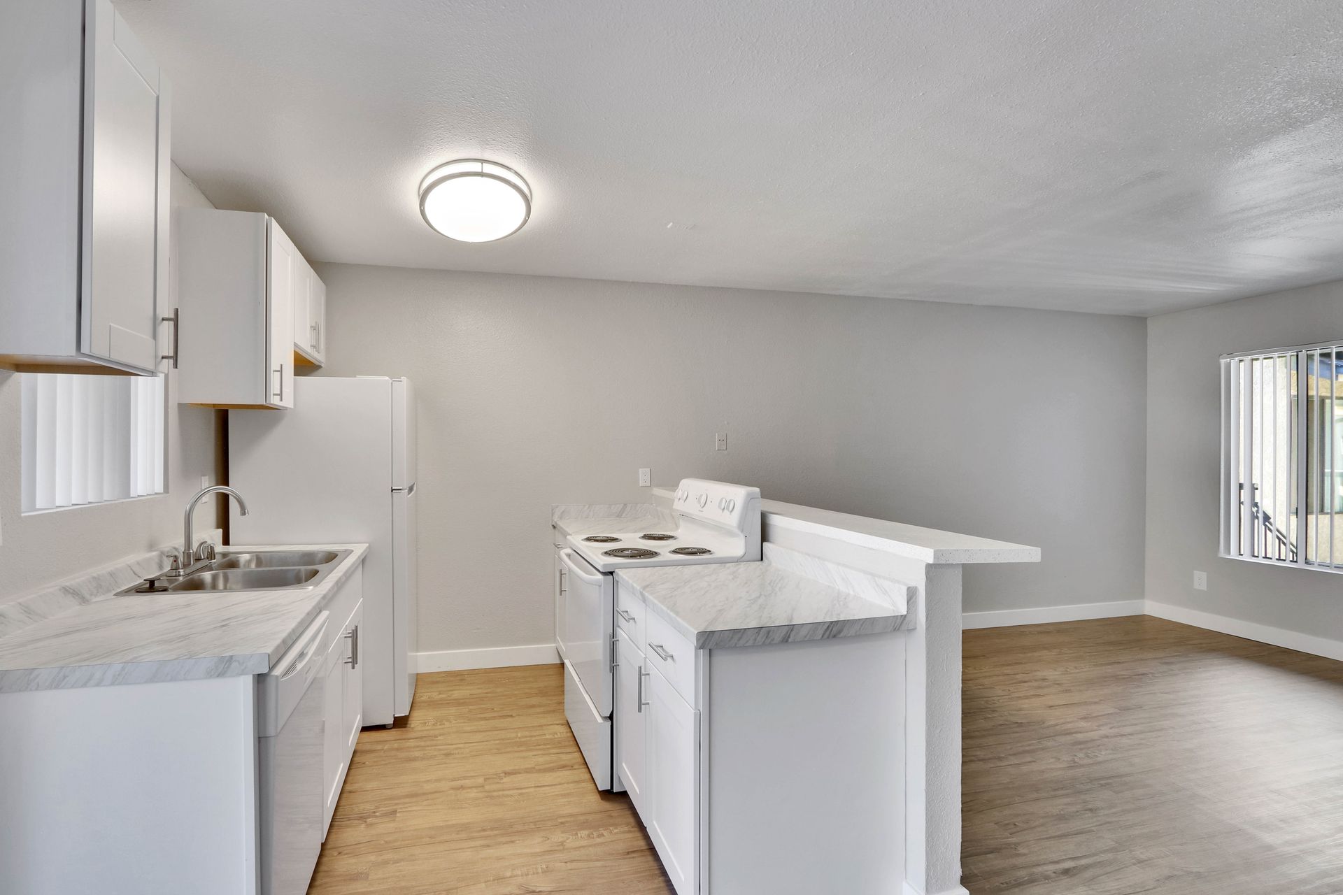 A kitchen with white cabinets , a stove , a refrigerator , and a sink.