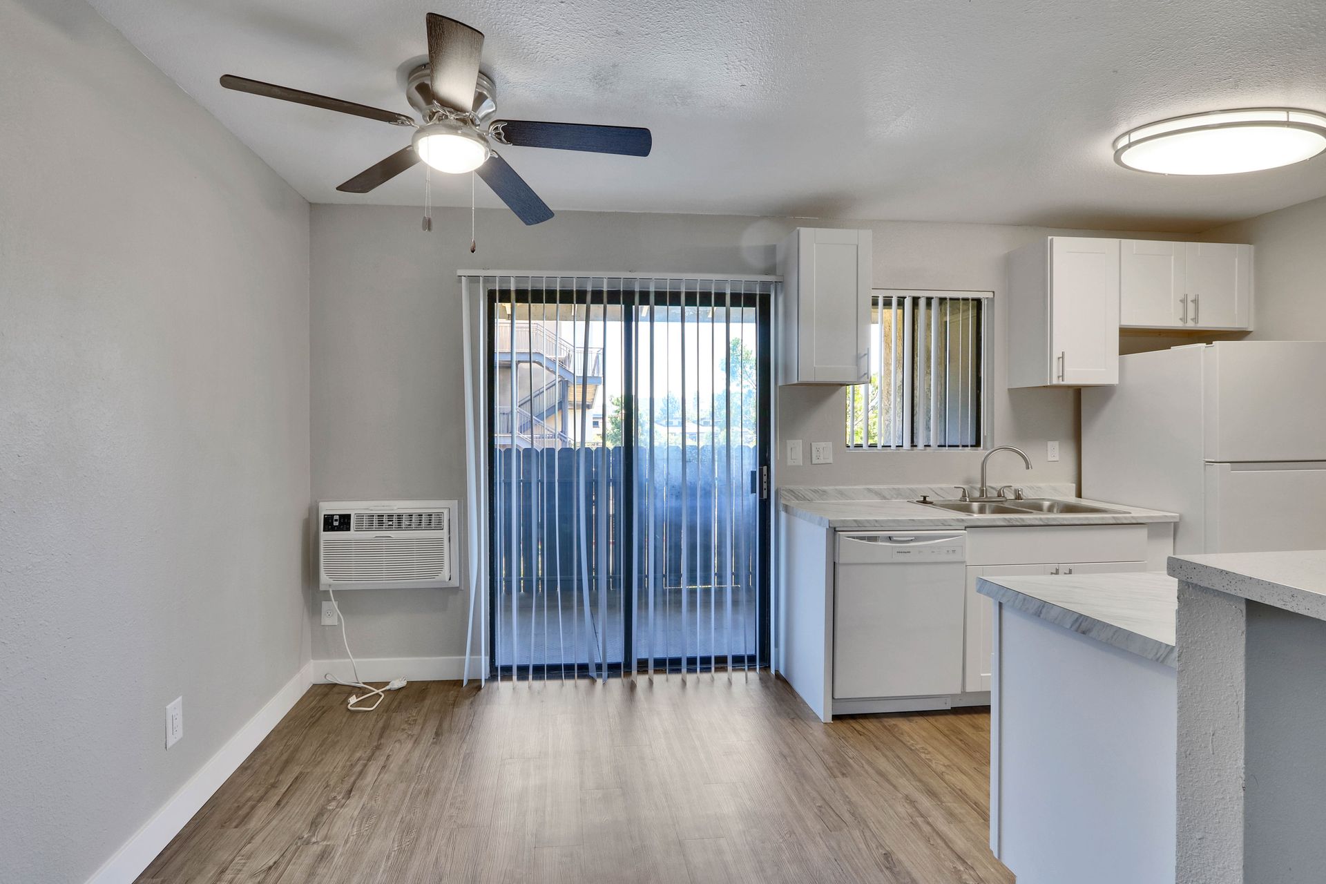 An empty apartment with a ceiling fan and sliding glass doors