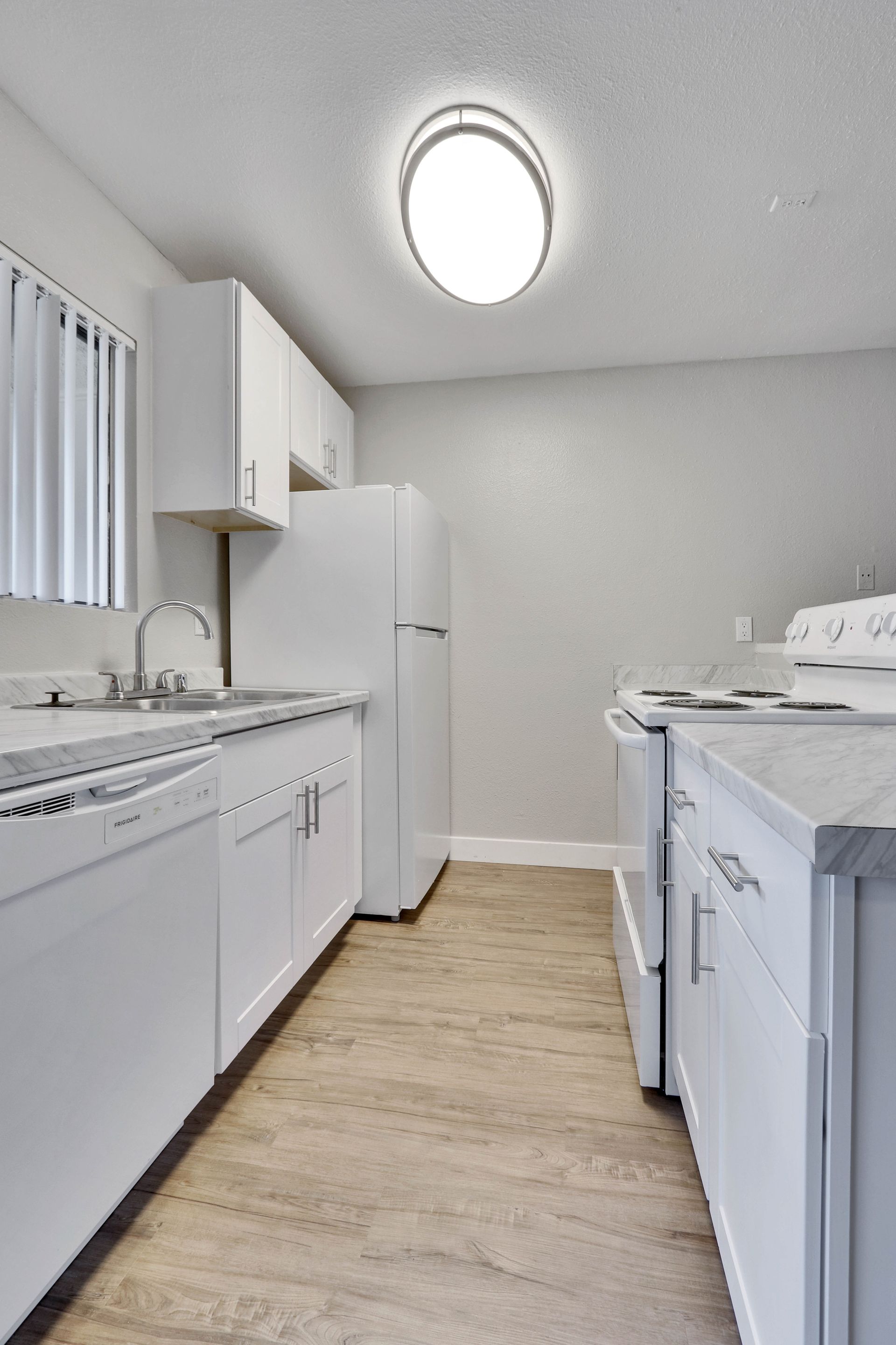 A kitchen with white cabinets , a refrigerator , stove and dishwasher.
