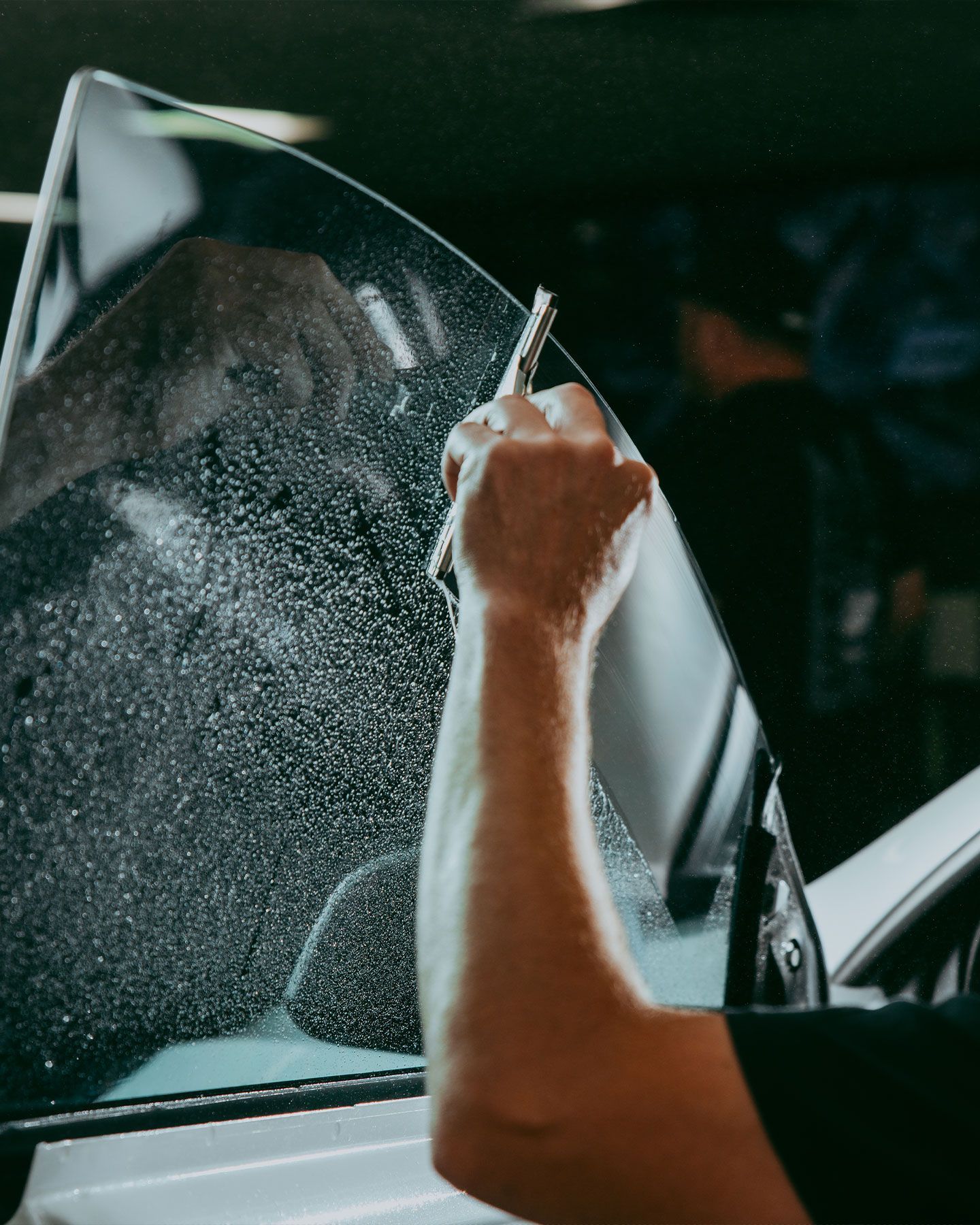 a man is applying tinted glass to a car window .