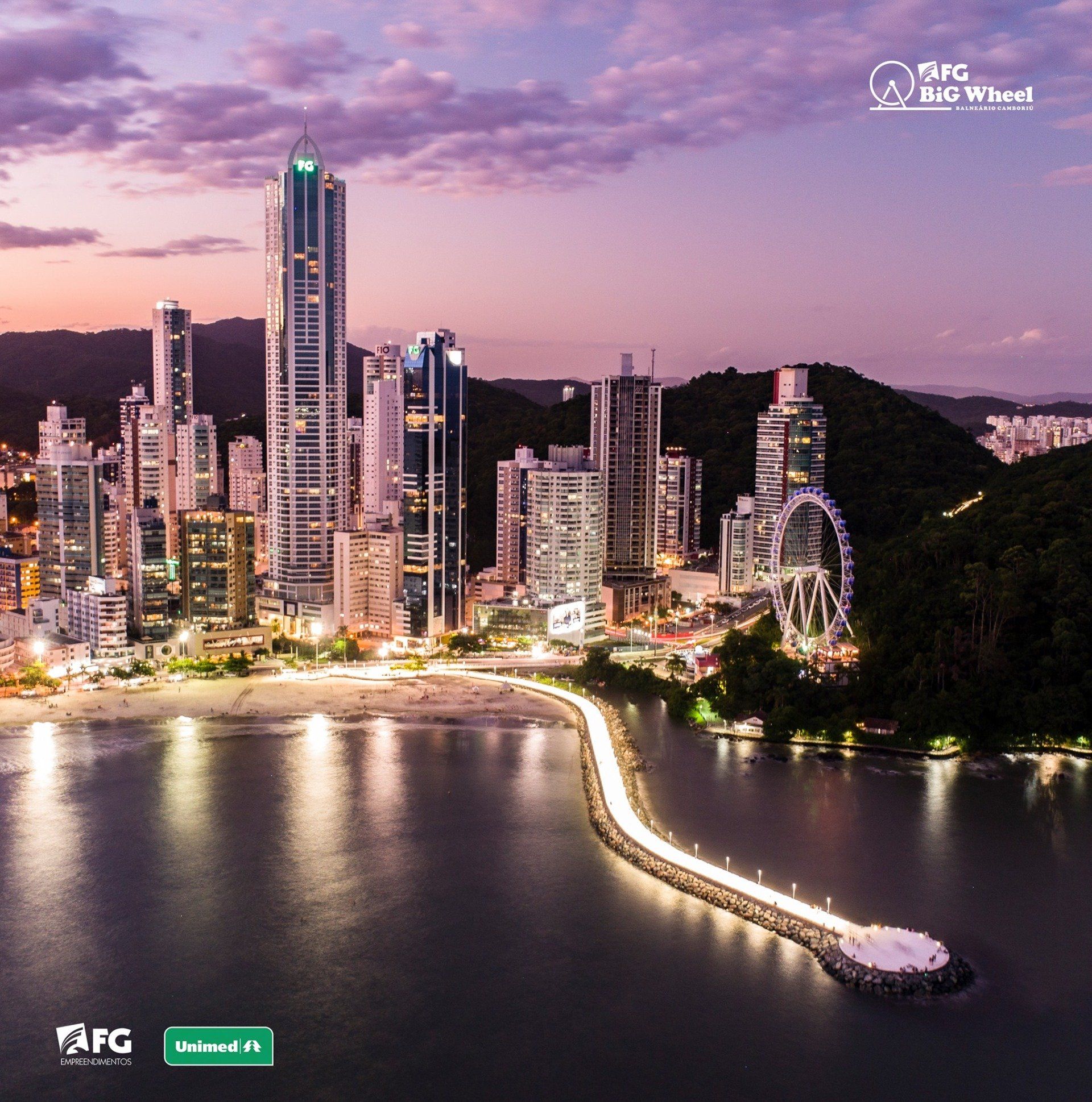 Horizonte da cidade ao entardecer, com roda gigante, píer iluminado e prédios.