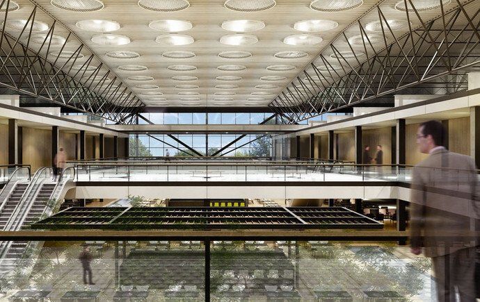 Interior espaçoso com pé-direito alto, claraboias e vários andares. Um homem passa.