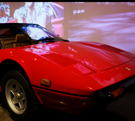 Ferrari conversível vermelha, estacionada, com interior marrom.