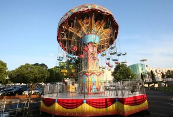 Um carrossel de balanços coloridos em um parque de diversões, com balanços suspensos sob uma grande cobertura.