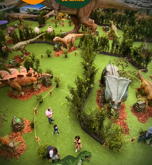 Campo de minigolfe com tema de dinossauros. Grandes figuras de dinossauros em grama verde, com pessoas jogando.