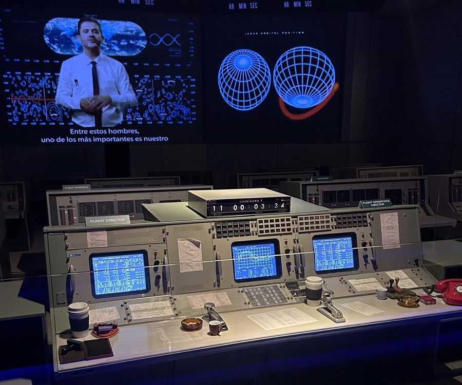 Exibição de sala de controle com tela, consoles e uma apresentação sobre o espaço.