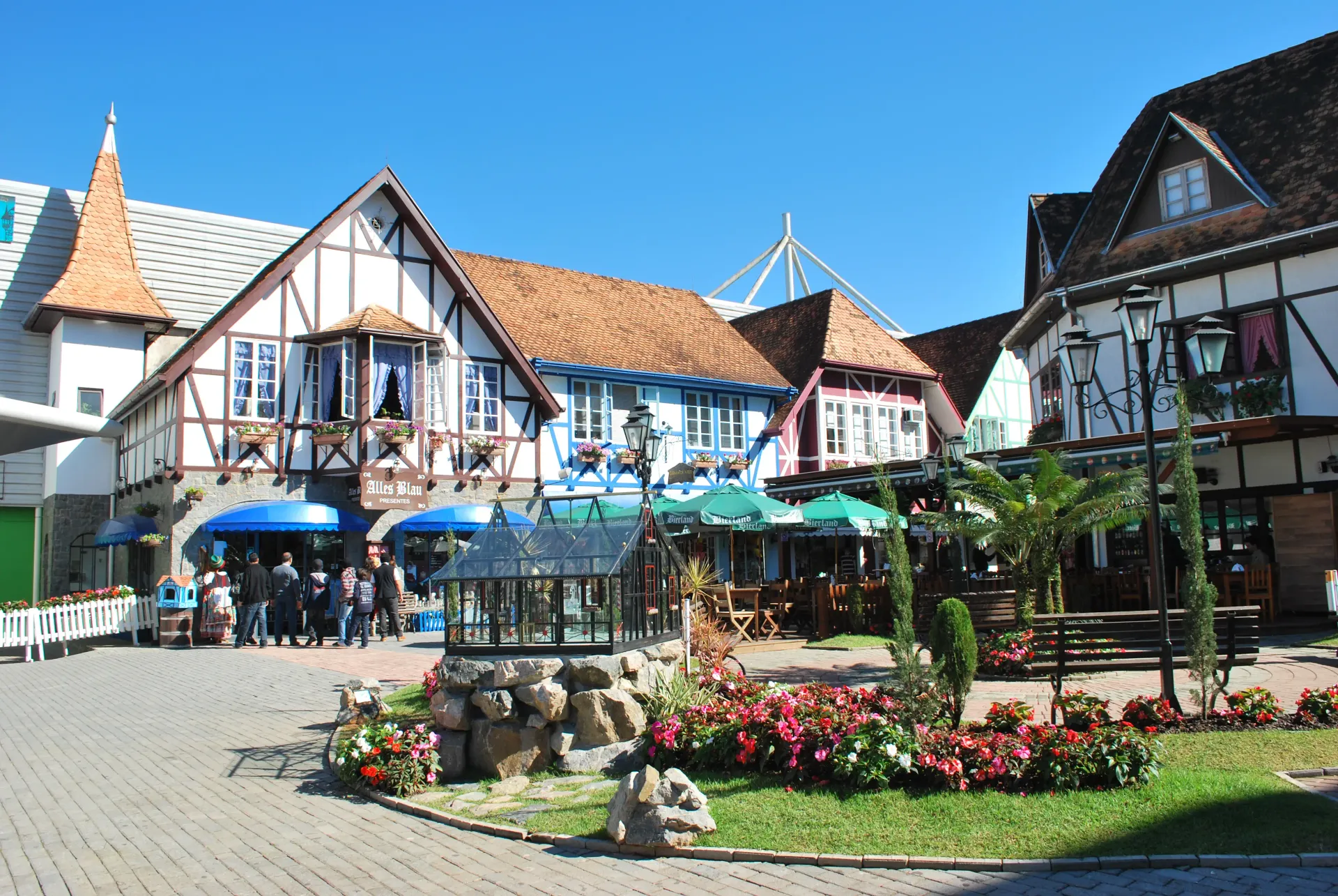 Edifícios em estilo europeu com canteiros de flores e um pátio central sob um céu azul claro.