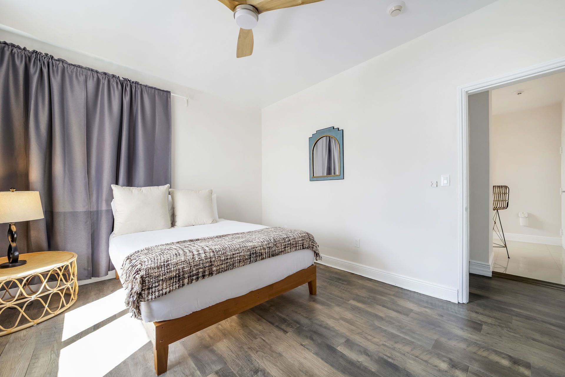 Bedroom with a bed, nightstand, curtains, and an arched mirror on the wall.