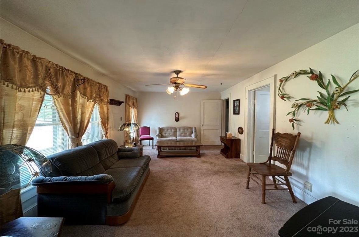 Living room with brown carpet, sofas, and decorative curtains.