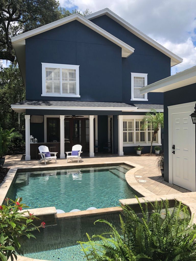 A construction worker on a scaffold in a room with exposed framing, gesturing.