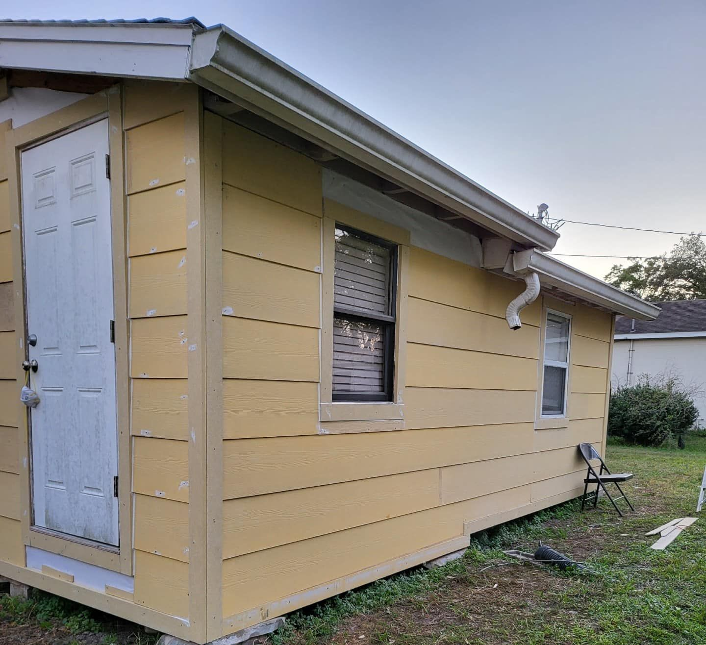 Bedroom with wood flooring, green accent wall, bed, and TV on a table by a window.