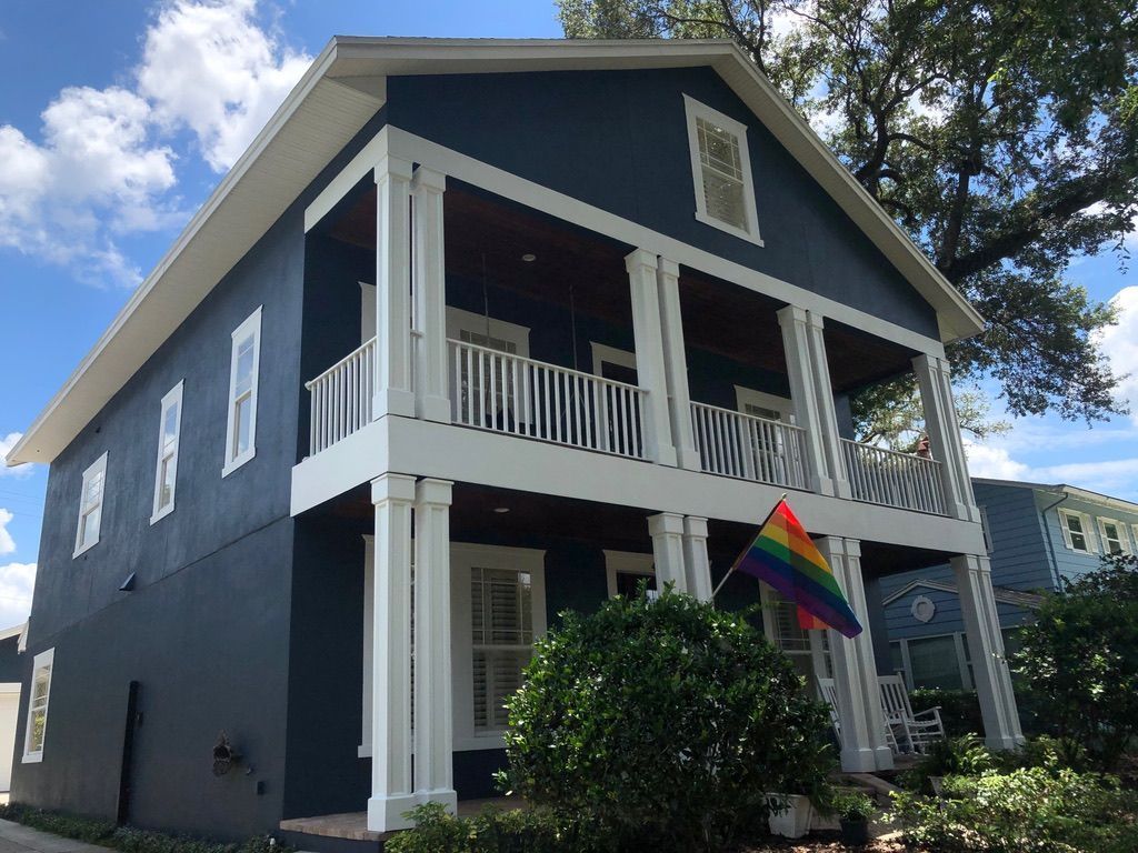 Person patching a wall inside a room with a wooden ceiling and window. Tools and materials are on the floor.