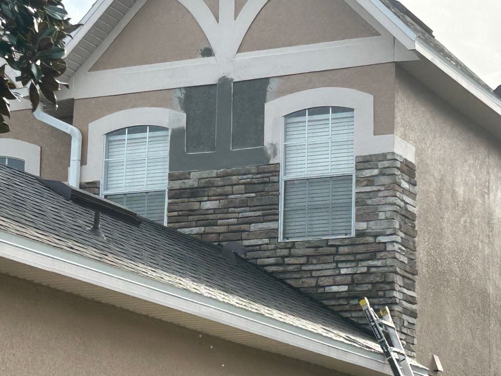 Tan house with green lawn, stone accents, palm trees, and a brick pathway.