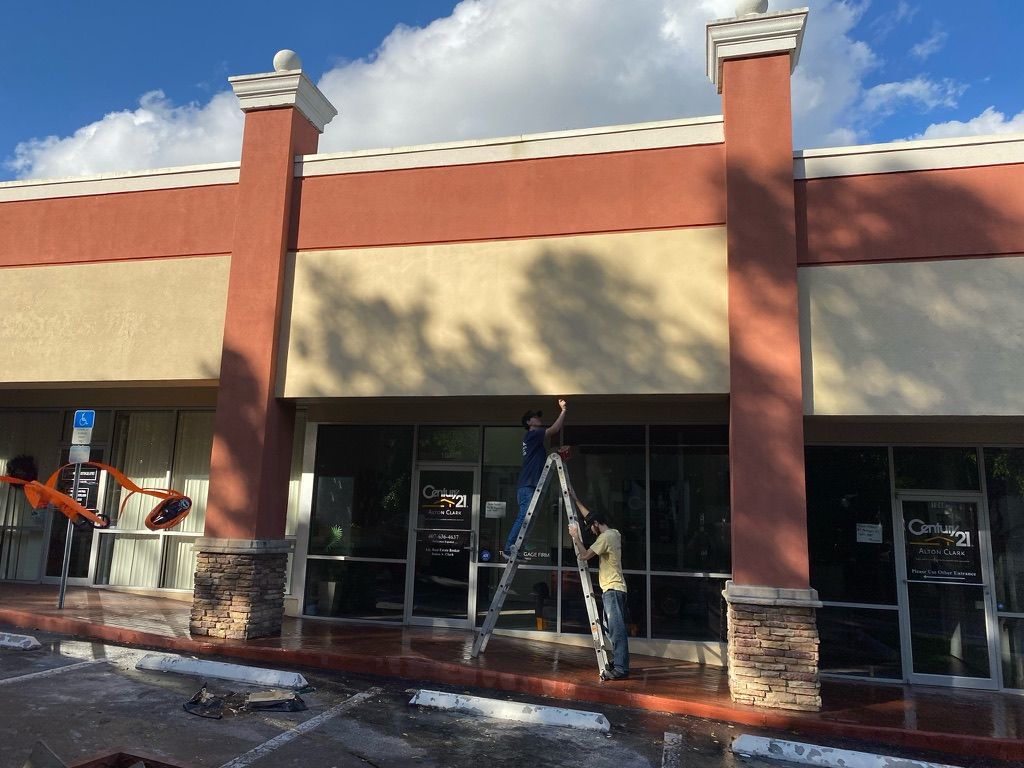 Tan house with green lawn, stone accents, palm trees, and a brick pathway.