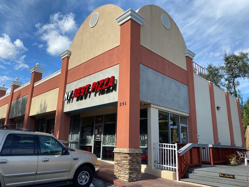 Damaged brick mailbox on a residential street; bricks are broken and fallen on the ground next to the post.