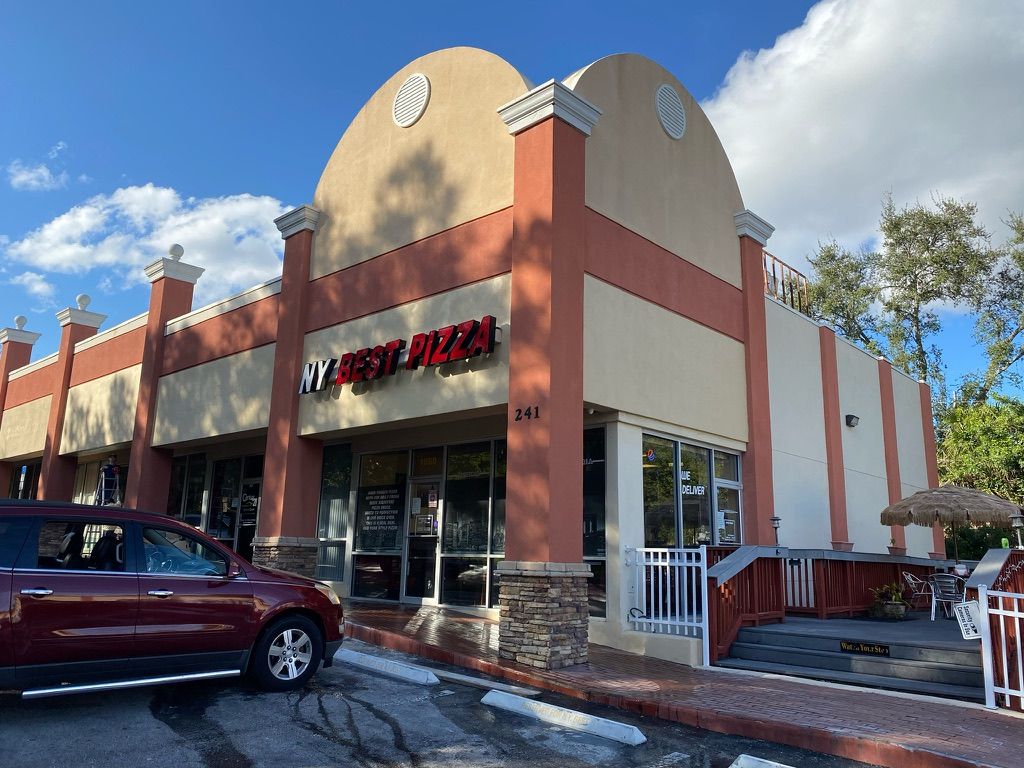 Brick mailbox with a post, fronting a grassy lawn and house.