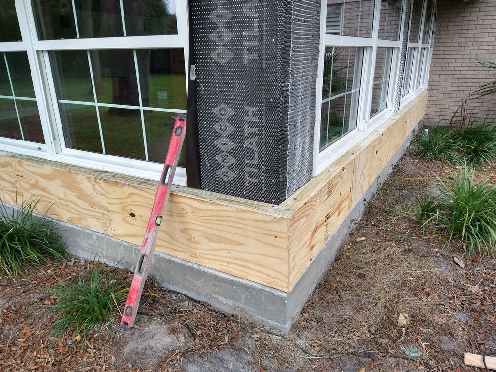 Tan house with green lawn, stone accents, palm trees, and a brick pathway.