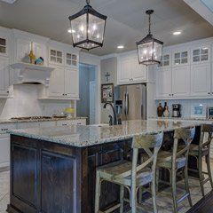 A kitchen with white cabinets , granite counter tops , and a large island.