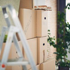 A ladder is sitting next to a pile of cardboard boxes.
