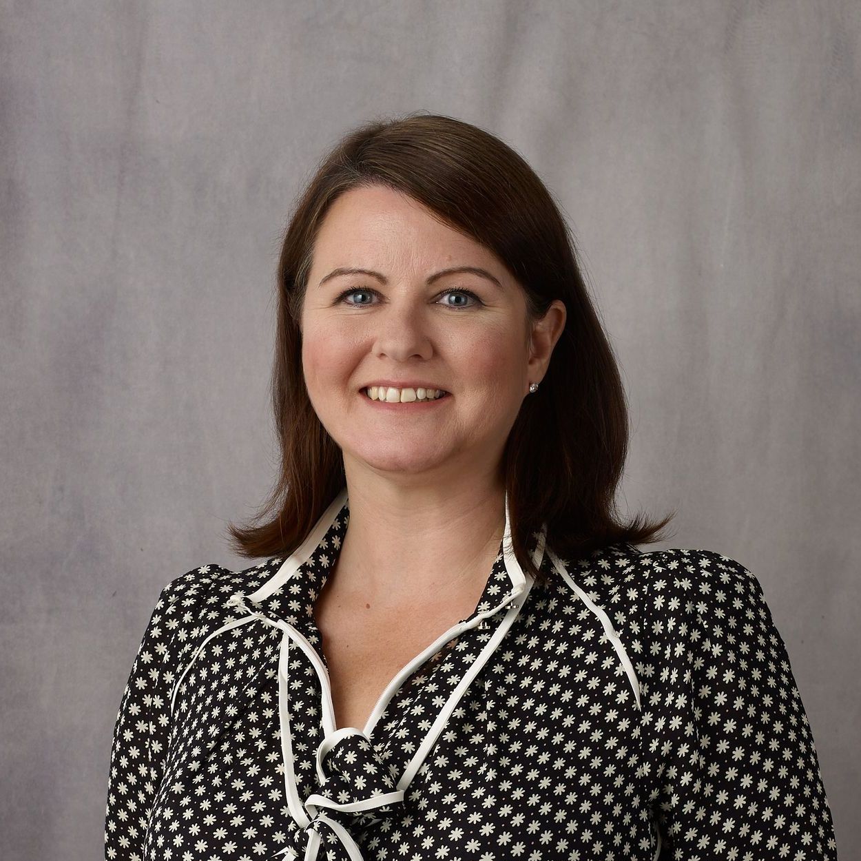 A woman in a black and white polka dot shirt smiles for the camera