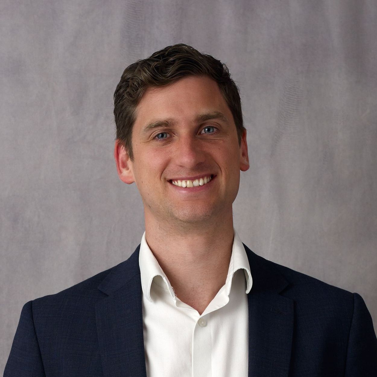 A man in a suit and white shirt is smiling for the camera