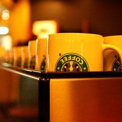 A row of yellow starbucks coffee mugs on a shelf
