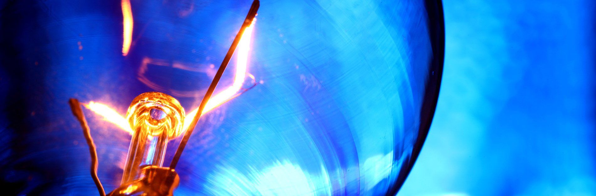 A light bulb is glowing in the dark with a blue background.