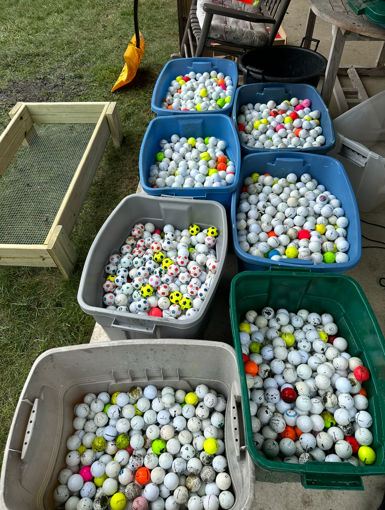 A bunch of buckets filled with golf balls of different colors.