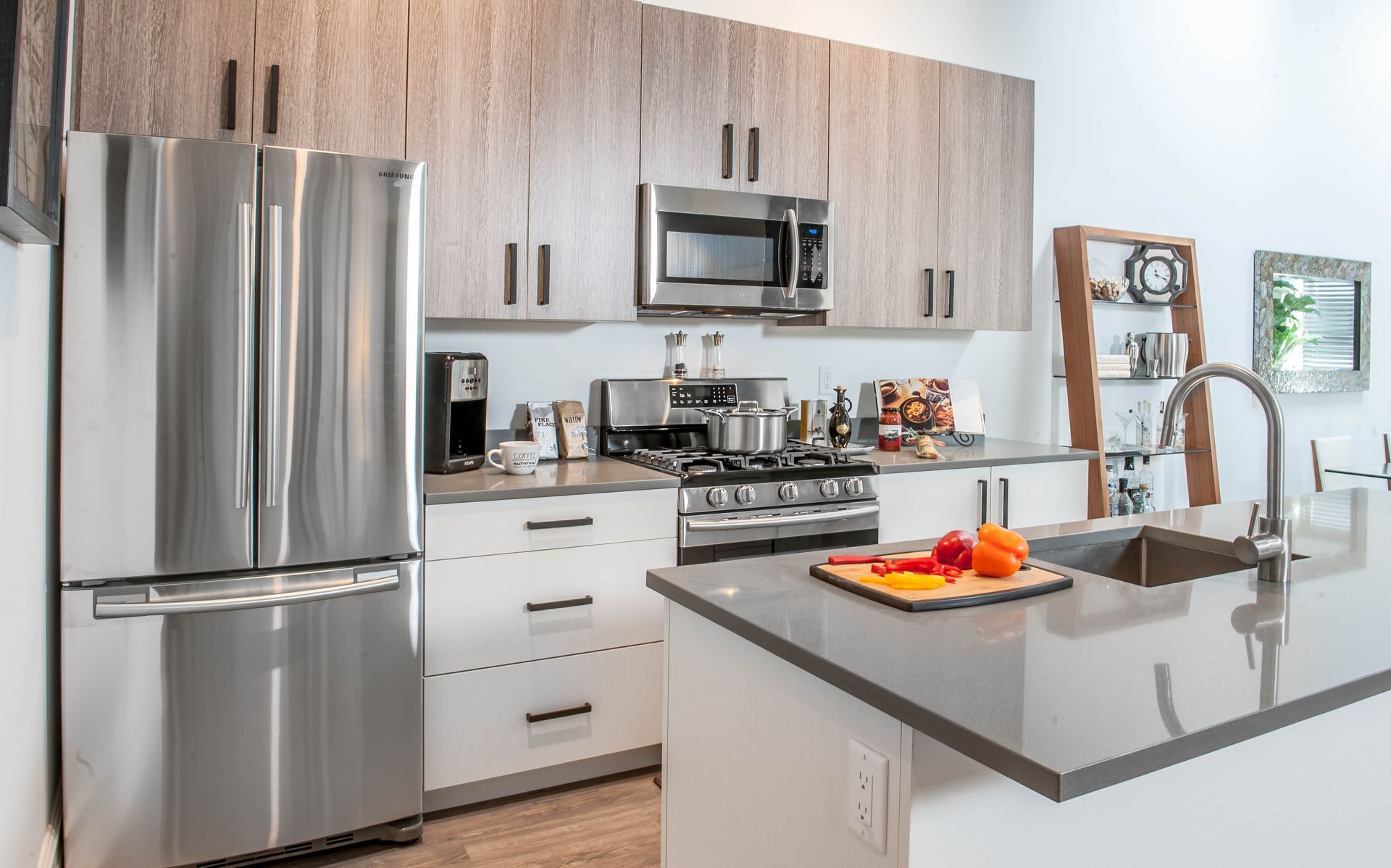 A kitchen with stainless steel appliances , wooden cabinets , a sink , and a refrigerator.