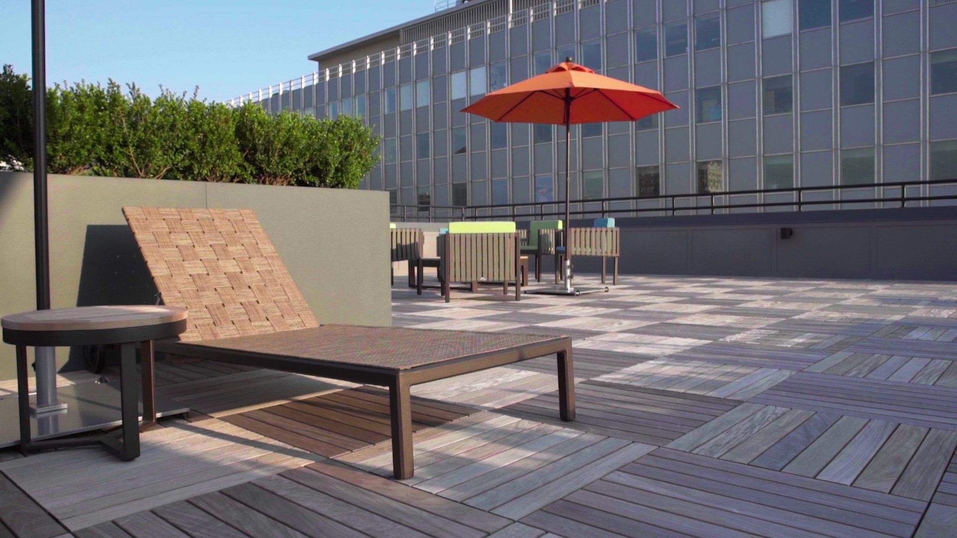 A rooftop deck with lounge chairs and an orange umbrella