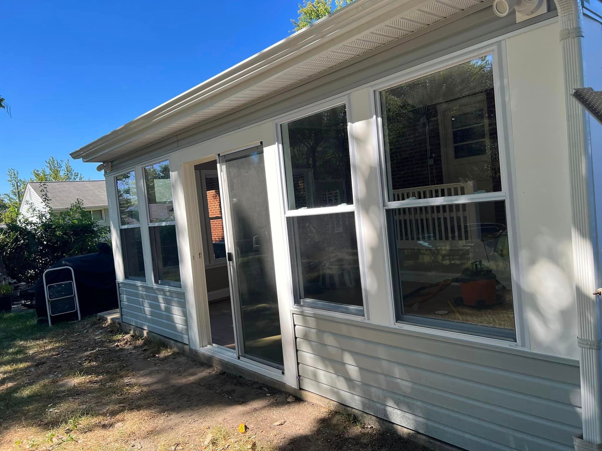 A white house with a lot of windows and a sliding glass door.