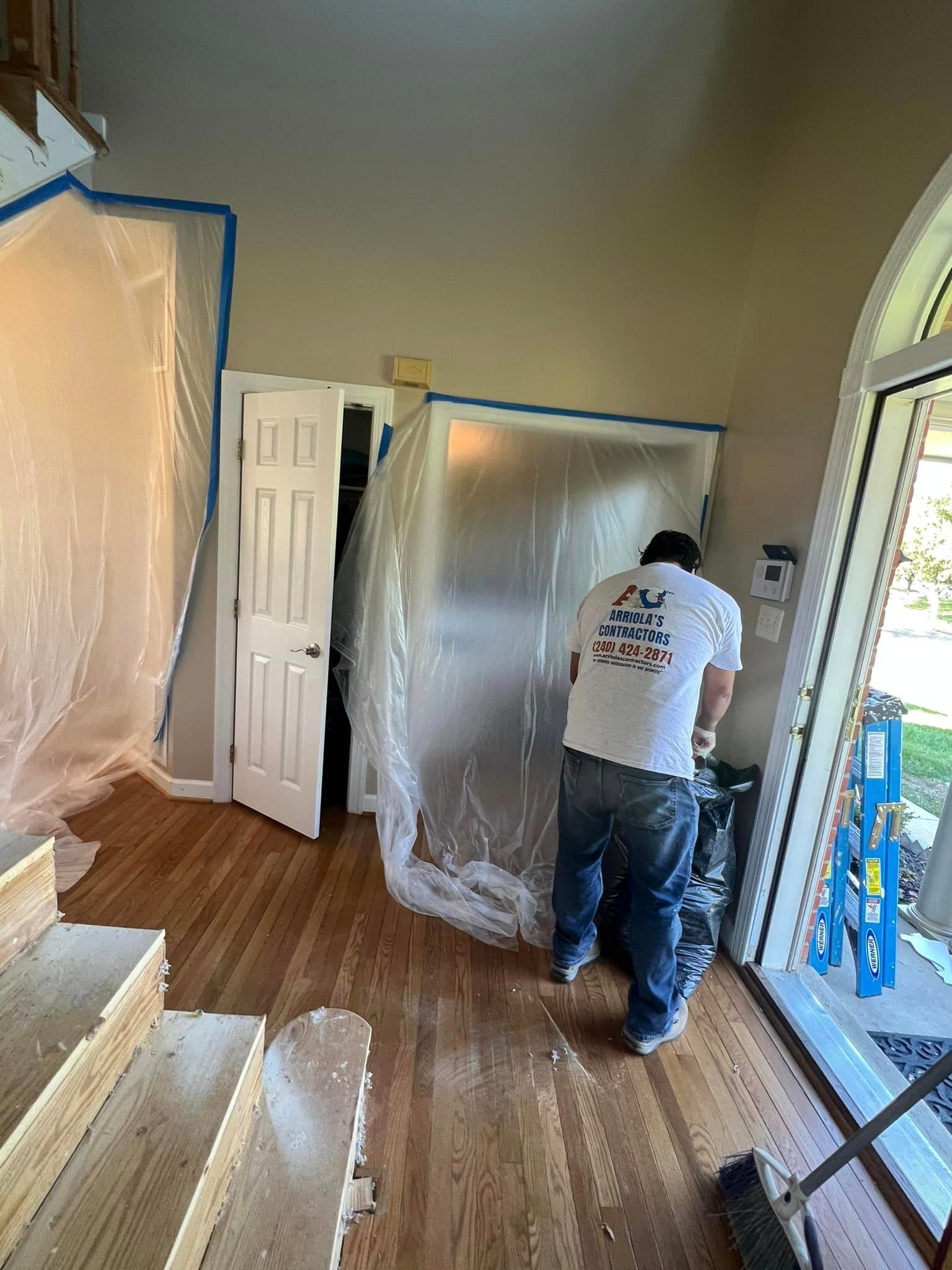 A man is standing in a room covered in plastic.