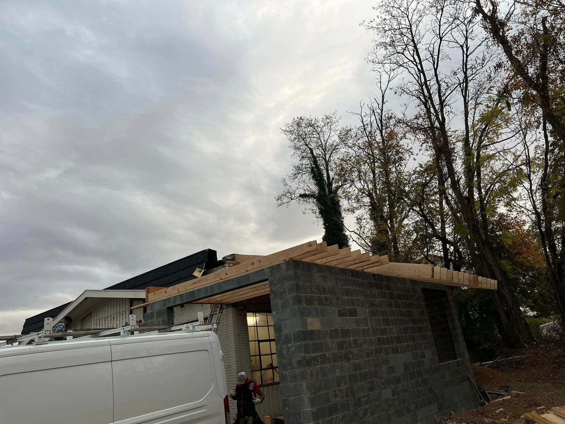 A white van is parked in front of a building under construction.