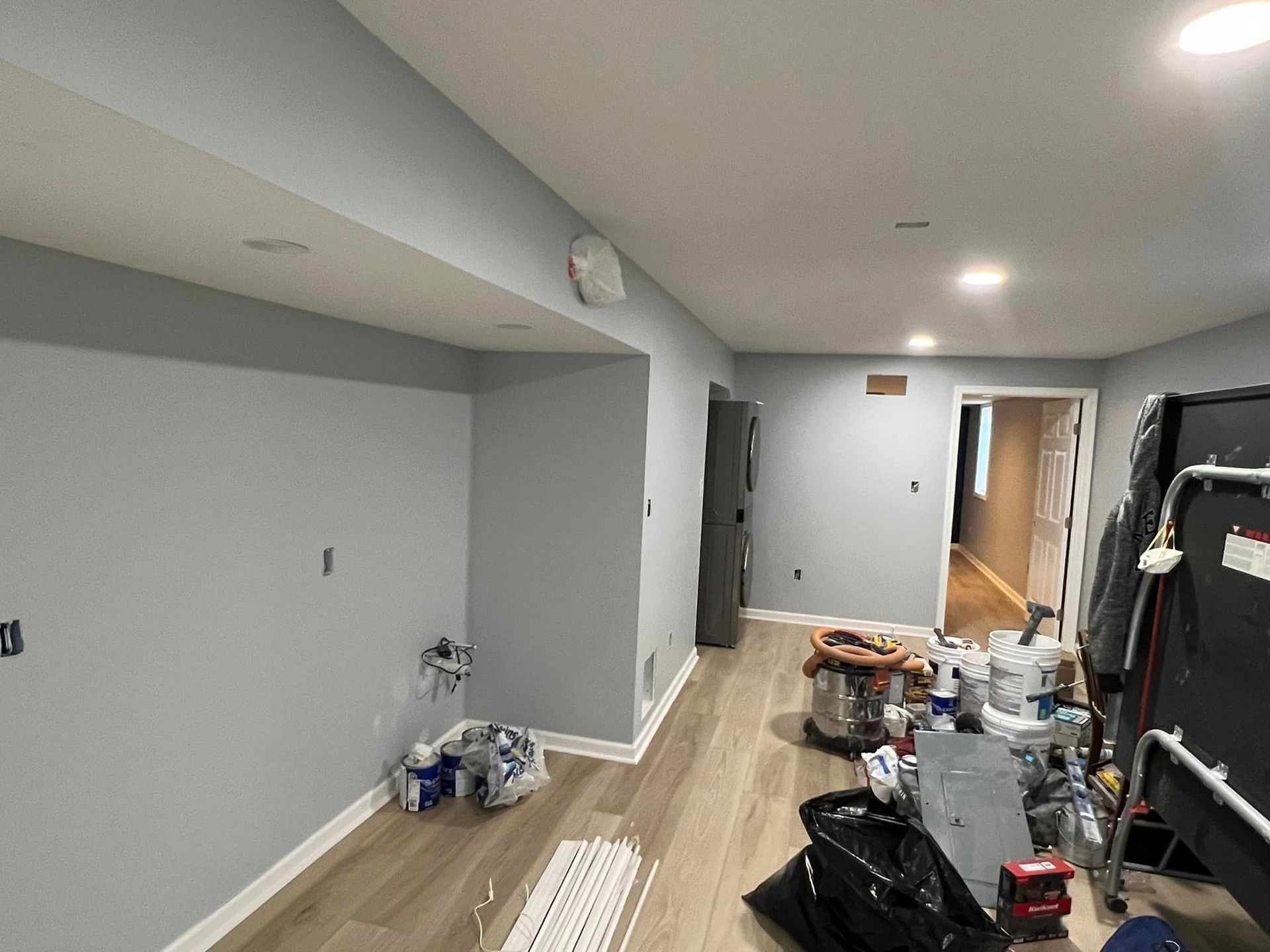 A room that is being painted with a lot of tools on the floor.