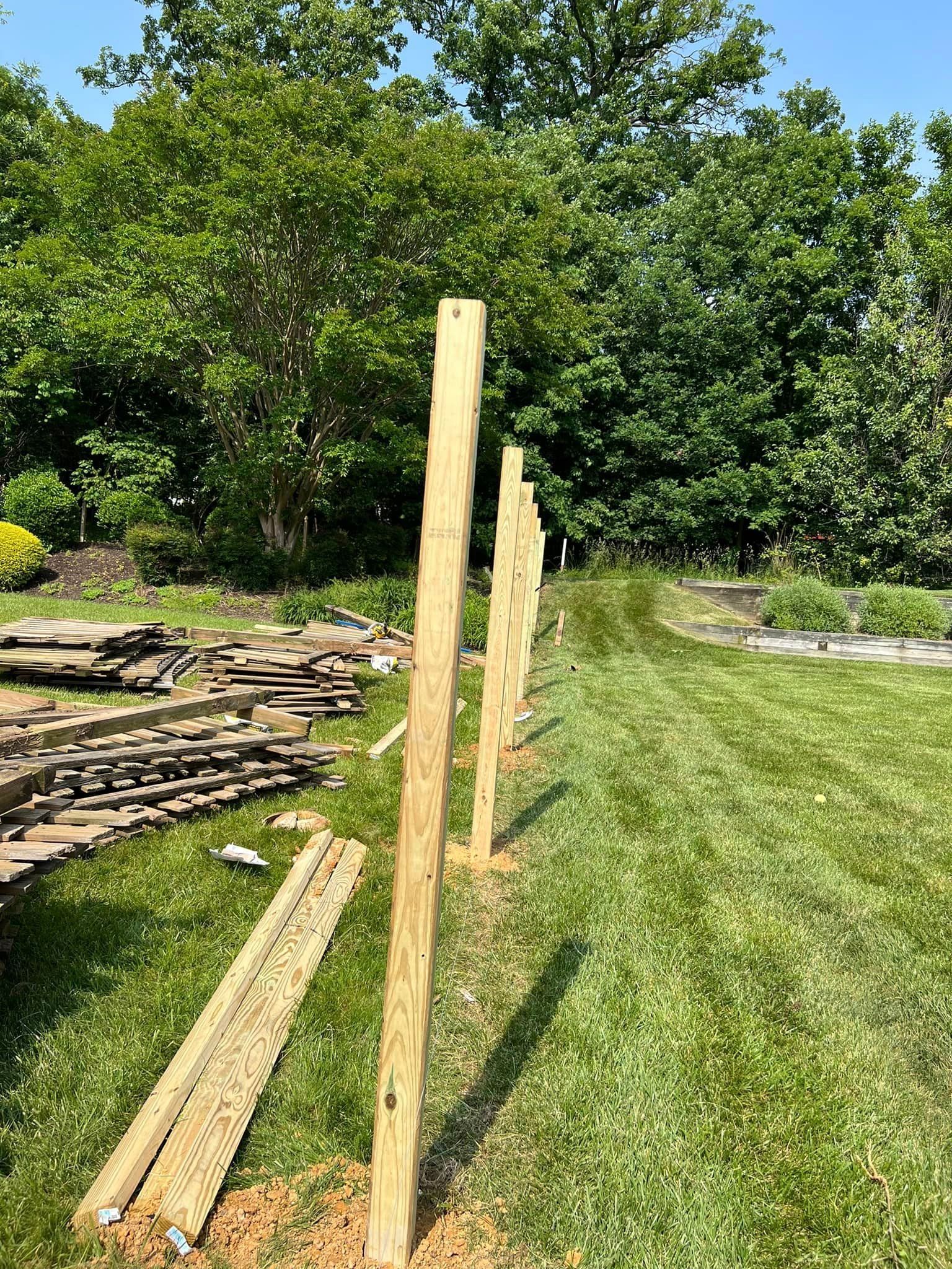 A wooden fence is being built in a lush green field.