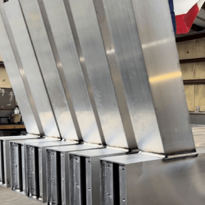 Silver metal industrial air duct sections aligned, possibly for commercial kitchen ventilation.