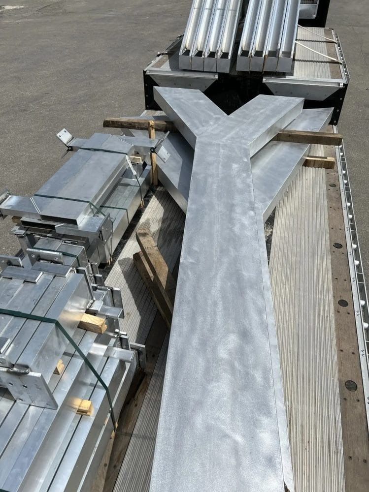 Large Y-shaped metal beams and other aluminum pieces loaded on a flatbed truck, ready for transport.